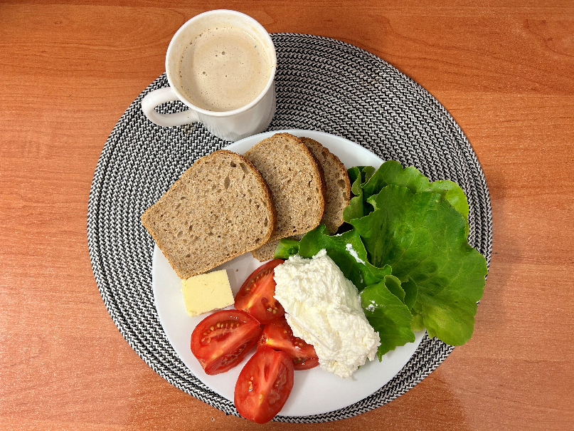 Na zdjęciu: Kawa z mlekiem, Chleb Graham, Masło extra 82%, Serek homo. naturalny, Pomidor, Sałata zielona